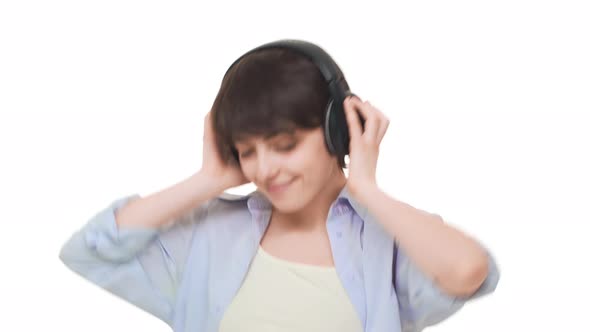 Young Caucasian Female with Short Haircut Listening Music Through Headphones with Pleasure Over