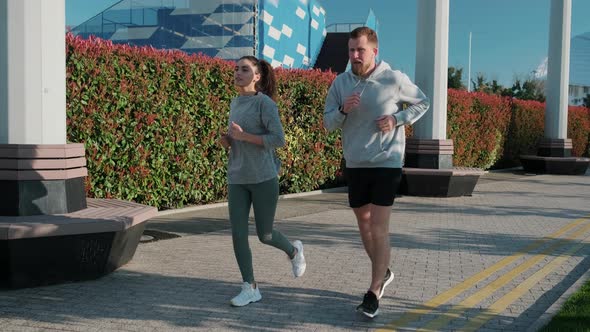 Morning Jog of Two Townspeople in Summer Day in City Park