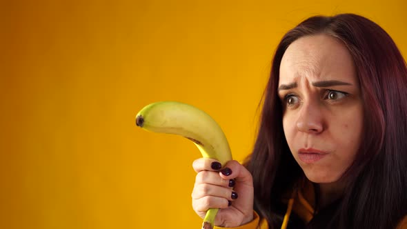 Portrait of Young Woman with Banana on Yellow Background