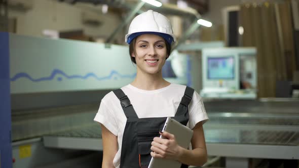 Portrait of Smart Young Manufacture Female Engineer in Helmet Holding Digital Tablet While Working