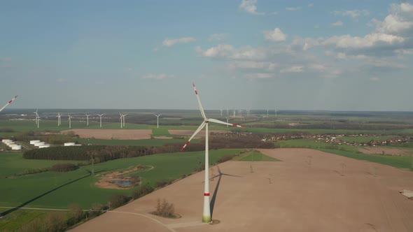 AERIAL: Close Up Circling Wind Turbine Under Construction Being Built on Rich Green Agriculture