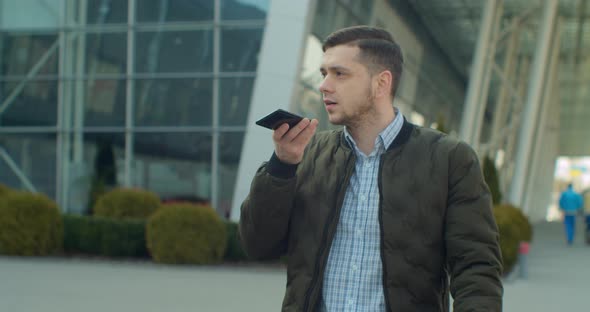 Man Using a Smartphone Voice Recording Function Online Walking on a City Street, Talking To Mobile