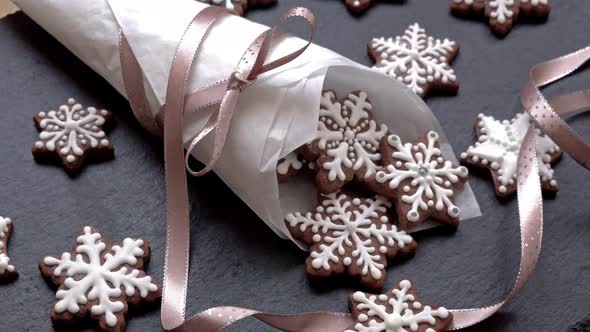 Side View of Rotating Gingerbread Cookies Snowflakes in a Paper Cone on Slate Table