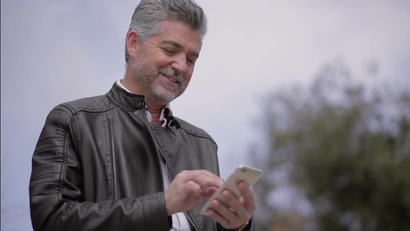 Smiling Mature Man Using Smartphone Outdoor