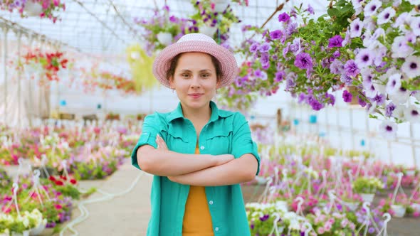 Front View of Young Agronomist Girl in Greenhouse Woman Crosses Arms Chest and Smiles Playfully