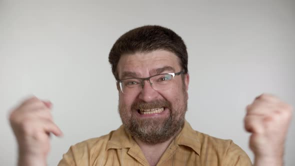 Emotional bearded aged man in yellow shirt isolated over gray background in studio.