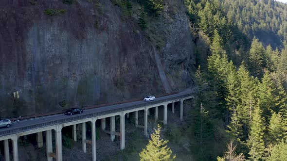 Aerial tracking shot of a car embarked on a road trip traveling on a scenic road in the mountains.