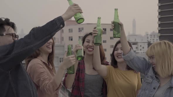 Group of young asian people dancing and raising their arms up played sunset on rooftop hanging out.