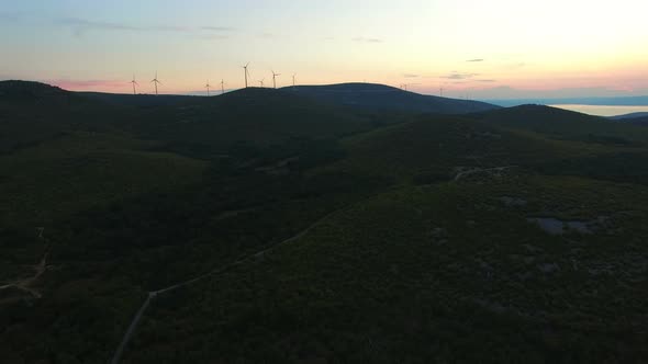 Sun setting behind hills with windmills in the background