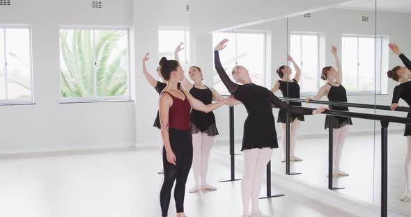 Caucasian ballet female dancers exercising with a barre by a mirror during a ballet class