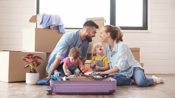 Caucasian Family, Man, Woman and Two Girls, Sit on Floor, Unpack Suitcase in New House.