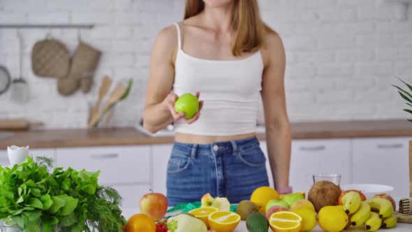 Woman kitchen portrait with fruits. Attractive athletic sportive woman standing in kitchen