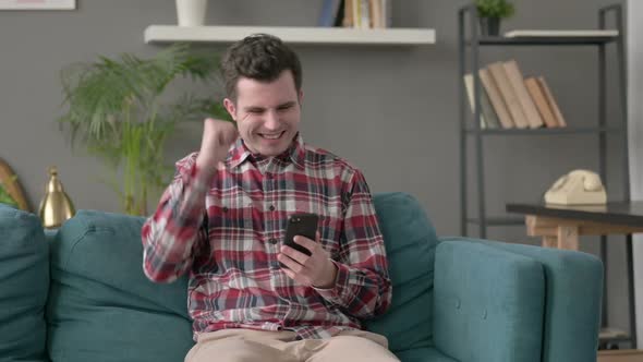 Man Having Success on Smartphone at Home