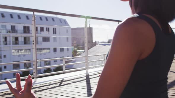 Mixed race gender fluid person practicing yoga meditation on roof terrace