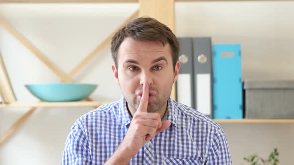 Gesturing of Silence By Man Sitting in Office