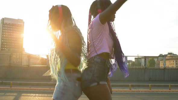 4k uhd two sisters black siblings outdoor city back light using smart phone listening music dancing
