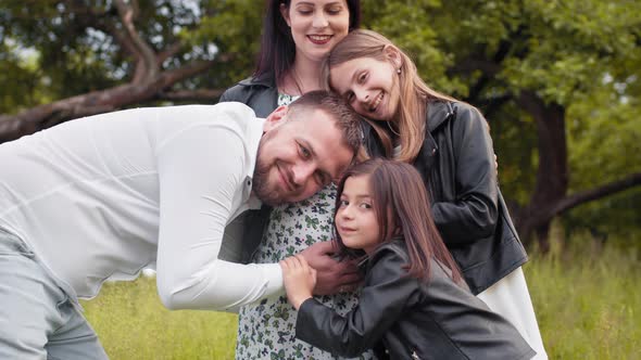 Handsome Man and Two Cute Sisters Embracing Pregnant Tummy of Beautiful Woman