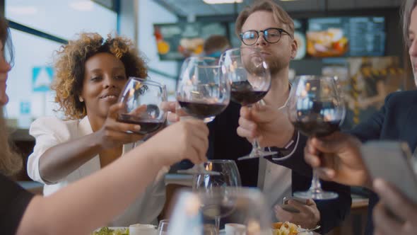 Man with Glass of Water Cheers with Diverse Friends Drinking Red Wine at Bar Restaurant