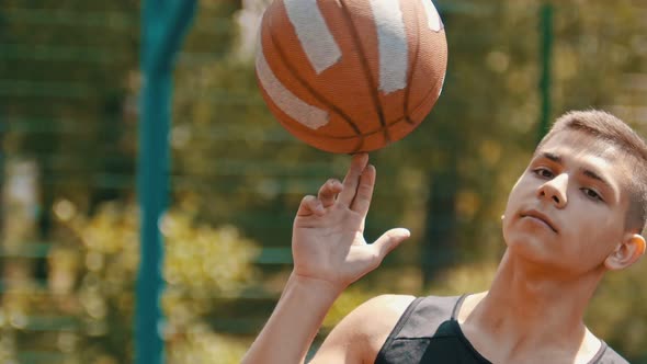 A Young Confident Man Standing on a Sports Ground and Spinning the Basketball Ball on His Finger