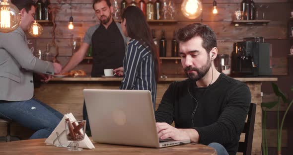 Young Handsome Man Typing a Message on His Laptop While Relaxing in a Vintage Coffee Shop