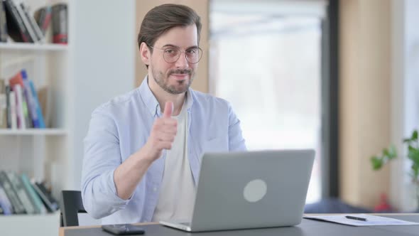 Thumbs Up By Man in Glasses with Laptop in Office