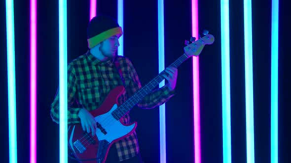 An Excited Guitarist Plays an Electric Guitar in a Studio Surrounded By Colorful Neon Tubes