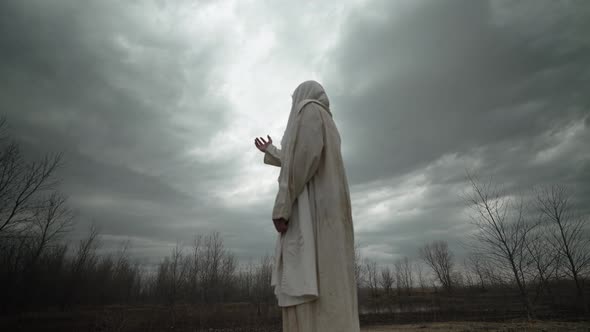 Religious Man In White Robe Raises Hand To Pray and Worship