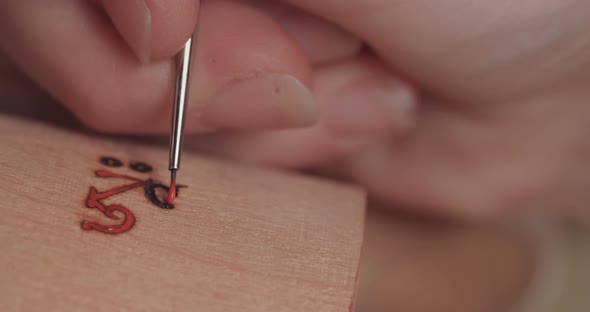 Artist painting and decorating a wooden Buddhist prayer wheel