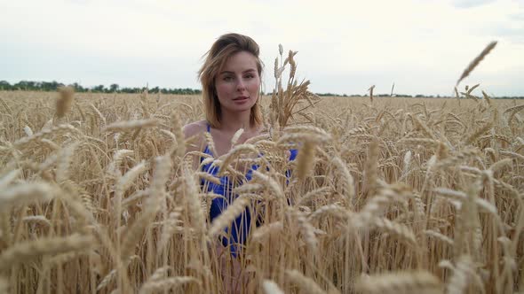 Beautiful Ukrainian Woman Wearing Dress in Ukrainian National Flag Colours Blue and Yellow at Wheat