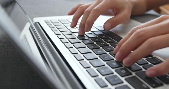 Hands using laptop type on keyboard