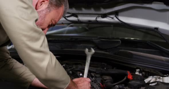 Mechanic standing with arms crossed while servicing a car engine