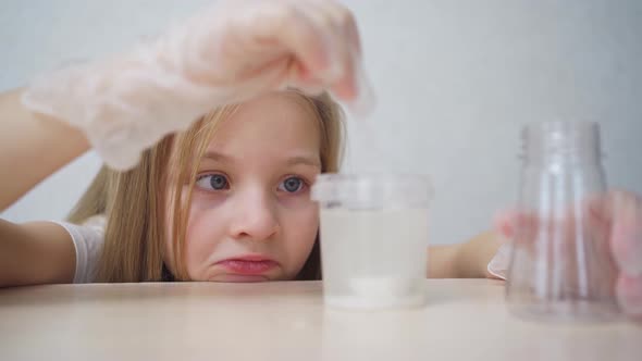 a Cute Little Girl in Protective Gloves Conduct an Experiments at Home alt