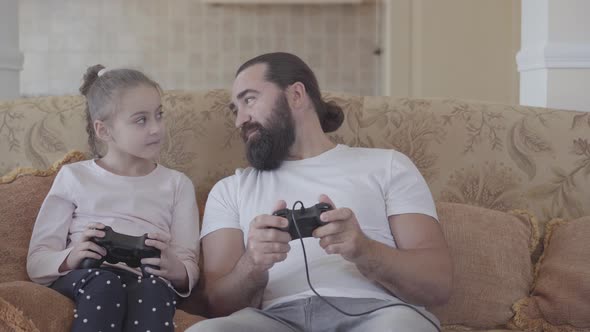 Small Daughter with Her Funny Father Playing Video Games on Tv with Great Emotions in Cozy Living