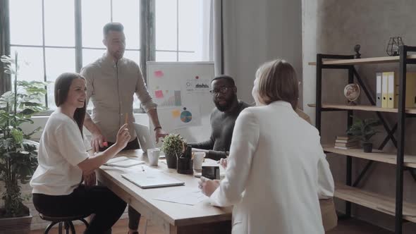 Team of Young Colleagues Conducting a Business Presentation Using Flipchart While Working in the