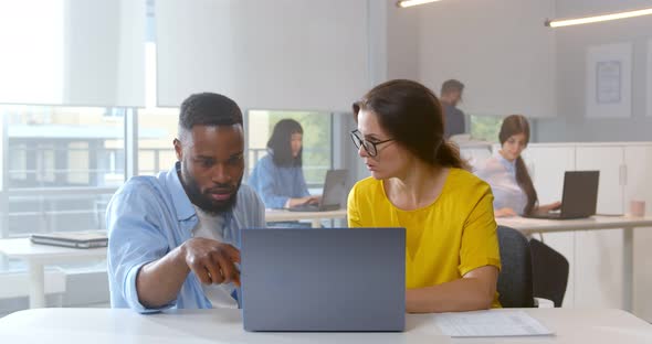 Diverse Colleagues at Office Discussing and Looking at Laptop Screen