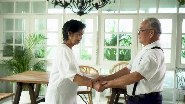 Old Senior Asian Couple Dancing and Smiling in Dinner Room