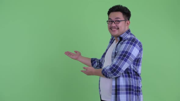 Happy Young Overweight Asian Hipster Man Showing To Back and Giving Thumbs Up