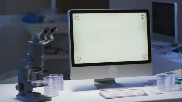 Desktop computer with illuminated screen at a workstation in an empty laboratory