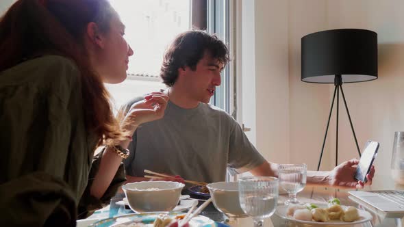 Couple eating at home and having video call on smartphone