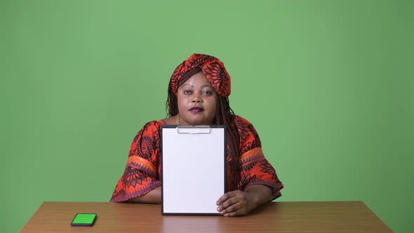 Overweight Beautiful African Woman Wearing Traditional Clothing Against Green Background