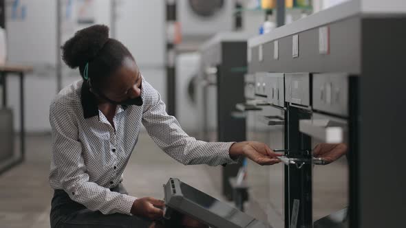 Female Shopper is Viewing Oven Before Buying Comparing Models and Choosing Best Device for Cooking