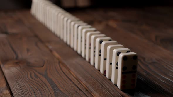 Hand of Pushing Dominoes on Brown Wooden Background