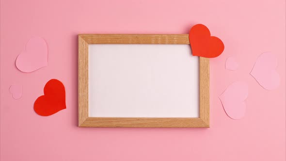 Stop motion animation mockup  of red and pink paper hearts on and near wooden frame on pink back