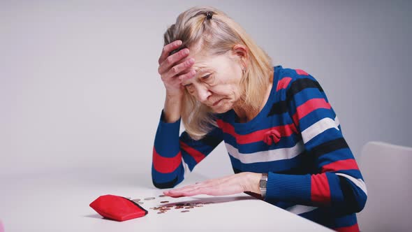 Sad Poor Elderly Woman Counting Coins and Looking at an Empty Wallet