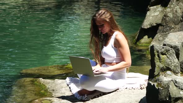 Well Looking Middle Aged Woman Typing on Laptop Keyboard Outdoors Near Lake in the Park