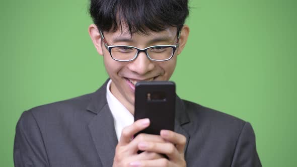 Young Happy Asian Businessman Smiling While Using Phone