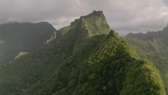 Aerial parallax shot of a dramatic mountain ridge covered by lush vegetation in French Polynesia