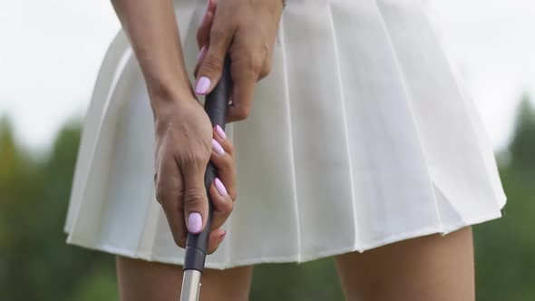 Woman golfer's hand holds the golf club in preparation for the hit. Close up.