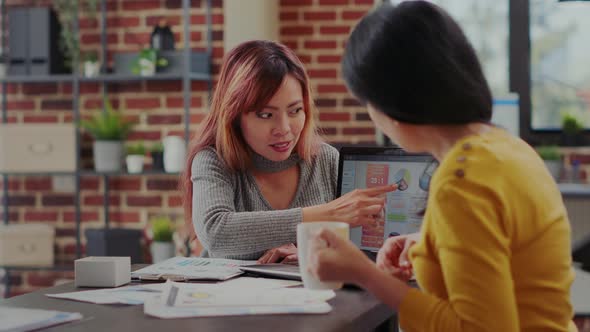 Team of Asian Women Analyzing Business Charts on Laptop