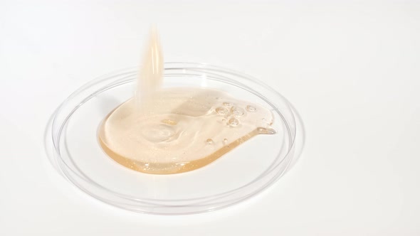 Transparent Cosmetic Gel Fluid Dripping Into the Glass Bowl of Petri alt
